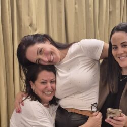שלוש חברות צוחקות ומתחבקות בערב נשים לבחור בשמחה