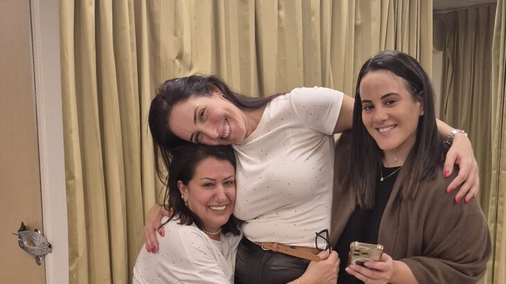 שלוש חברות צוחקות ומתחבקות בערב נשים לבחור בשמחה
