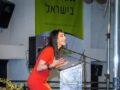 הילה עשור צוחקת ליד הפודיום בהרצאה