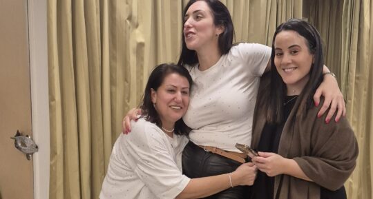 שלוש נשים מתחבקות וצוחקות בערב נשים