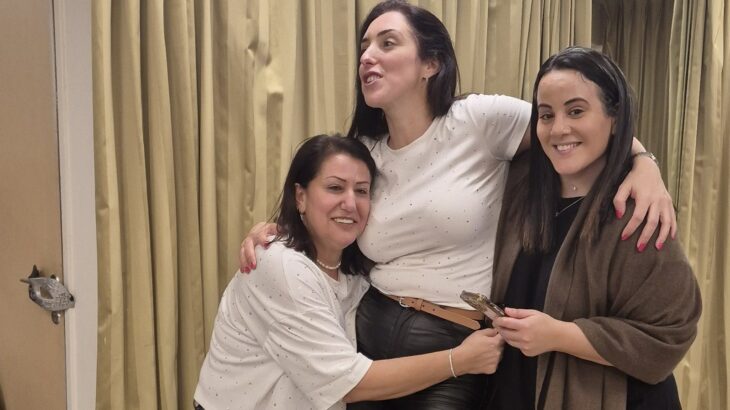 שלוש נשים מתחבקות וצוחקות בערב נשים