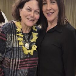 שתי חברות מחייכות, אחת עם זר פרחים, בערב נשים