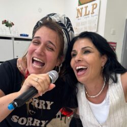 שתי חברות שרות וצוחקות למיקרופון בערב נשים