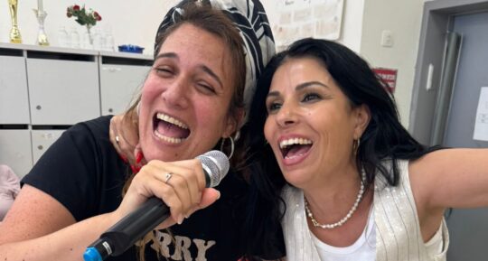 שתי חברות שרות וצוחקות למיקרופון בערב נשים