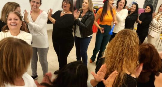 נשים צוחקות ומוחאות כפיים במעגל בערב נשים