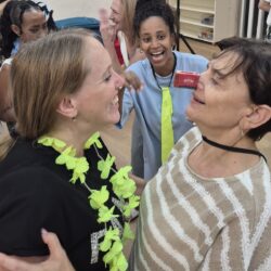 שתי נשים צוחקות פנים מול פנים עם שרשראות פרחים בערב נשים