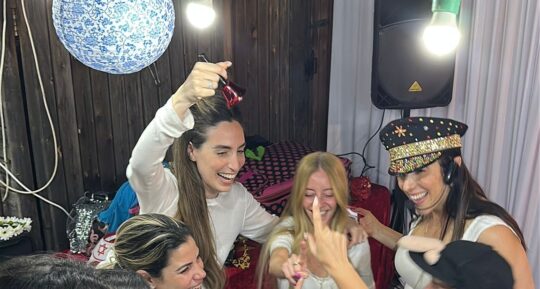 החברות מתקבצות סביב הכלה באמצע משחק, אחת מצלצלת בפעמון